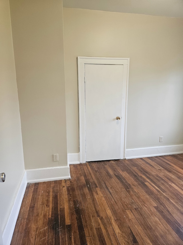 spare room featuring baseboards and wood-type flooring