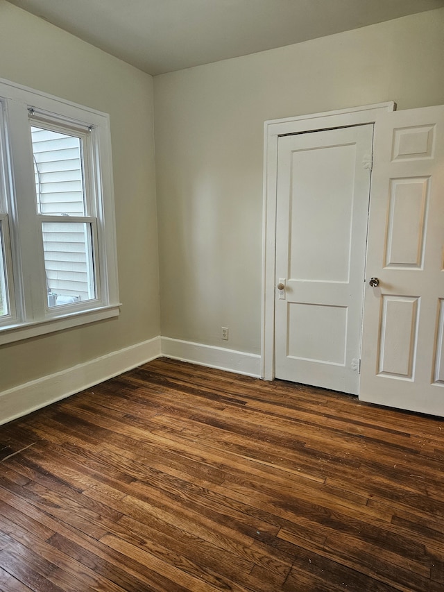 empty room featuring baseboards and dark wood-style floors