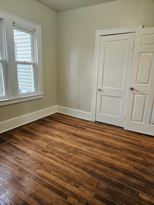 unfurnished room with baseboards, plenty of natural light, and dark wood-style floors