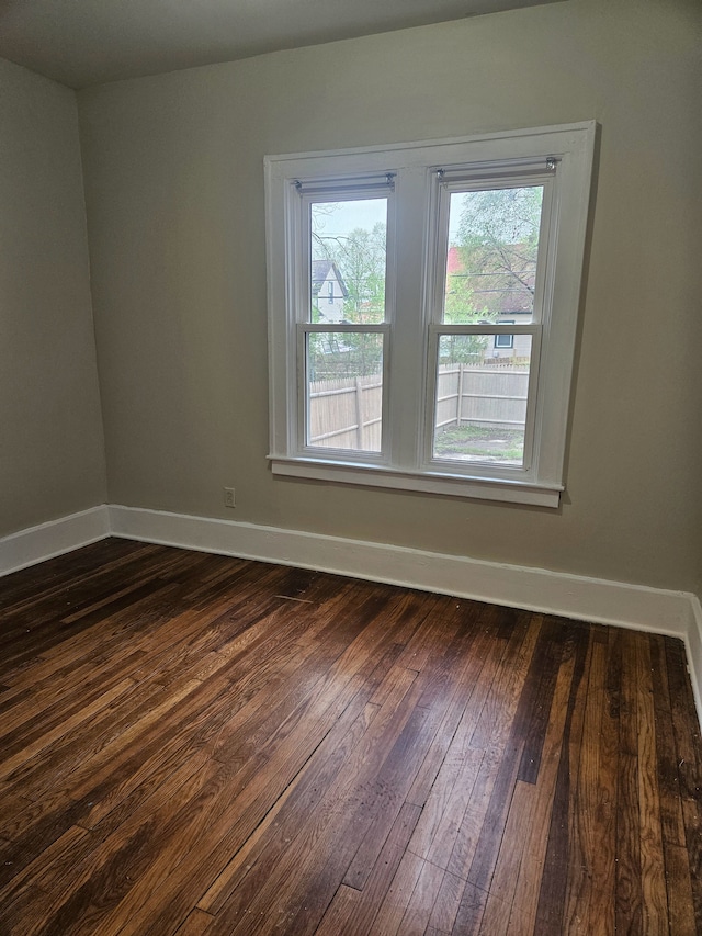 empty room featuring baseboards and dark wood-style floors