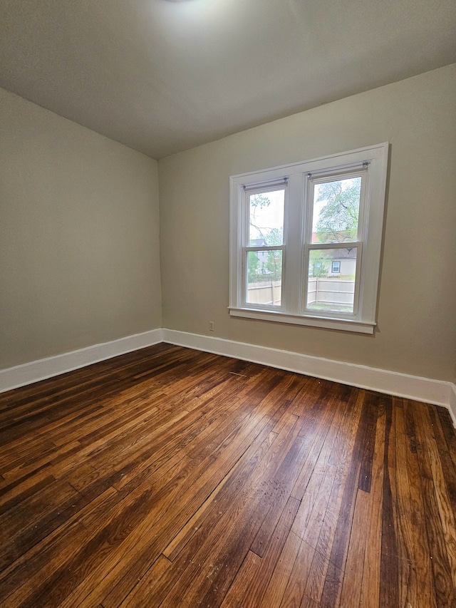 unfurnished room with baseboards and dark wood-style floors