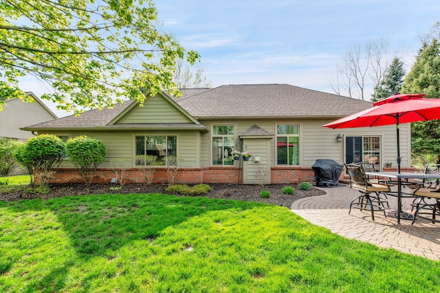 rear view of property with a patio, a lawn, and a shingled roof