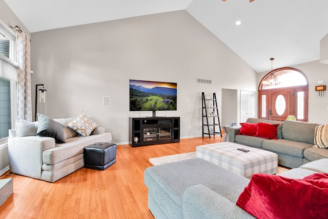 living room with high vaulted ceiling, light wood-style flooring, and baseboards