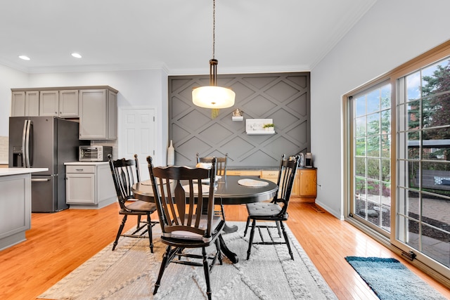 dining area with crown molding, light wood-style flooring, baseboards, recessed lighting, and an accent wall