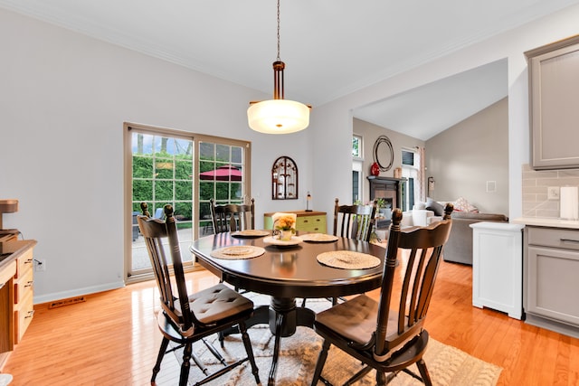 dining room with ornamental molding, visible vents, vaulted ceiling, baseboards, and light wood-style floors