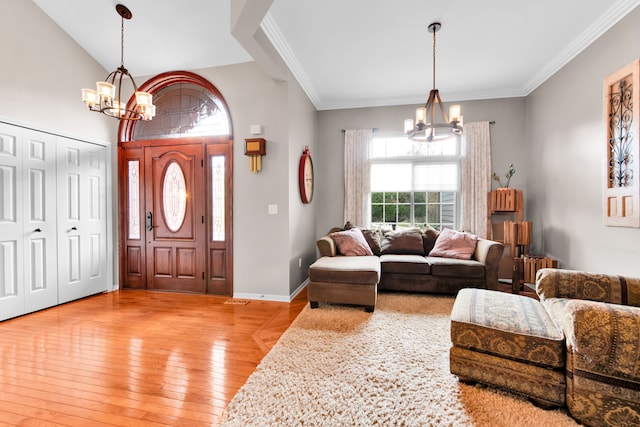 foyer with a chandelier, light wood-style flooring, crown molding, and baseboards