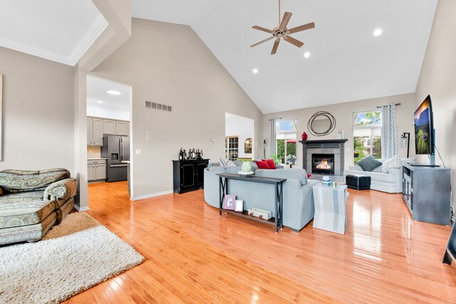 living room with high vaulted ceiling, ceiling fan, a tile fireplace, light wood-style floors, and recessed lighting
