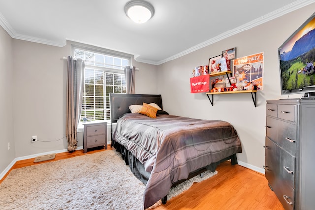 bedroom featuring light wood finished floors, ornamental molding, and baseboards