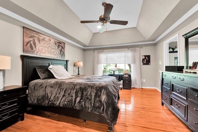 bedroom with baseboards, a raised ceiling, light wood-style flooring, and a ceiling fan