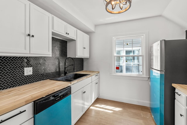 kitchen featuring dishwasher, a sink, freestanding refrigerator, wood counters, and tasteful backsplash
