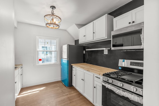 kitchen featuring appliances with stainless steel finishes, white cabinets, a chandelier, and lofted ceiling