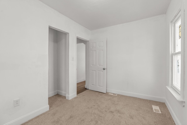 unfurnished bedroom with carpet, multiple windows, and baseboards