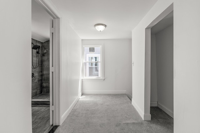 hallway featuring carpet flooring and baseboards
