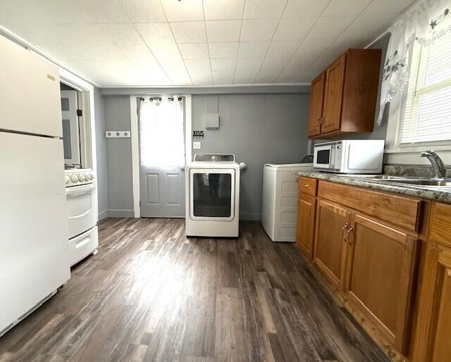 clothes washing area featuring laundry area, washing machine and dryer, a sink, and dark wood-style floors