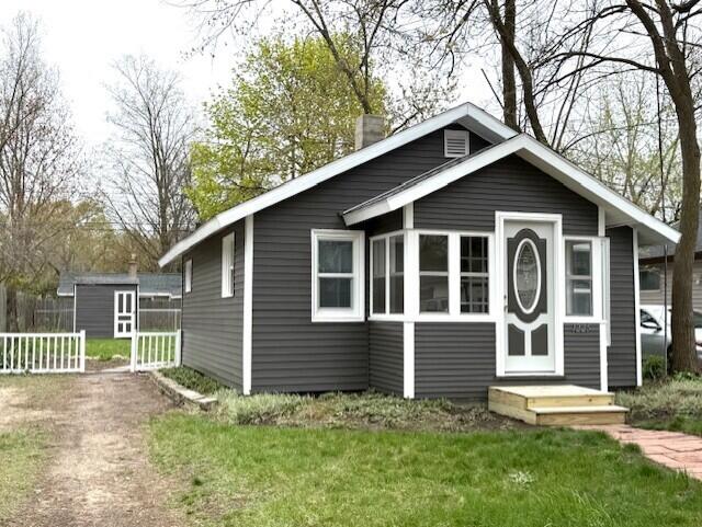 view of front of home featuring a chimney, an outdoor structure, a front lawn, and fence