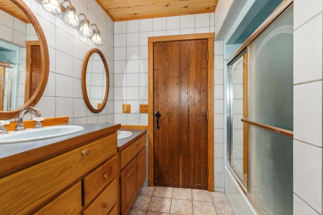 full bathroom with a sink, tile walls, tile patterned floors, shower / bath combination with glass door, and double vanity