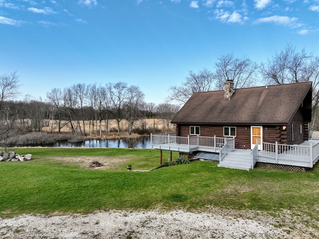 back of house with a yard, a chimney, log exterior, and a deck with water view