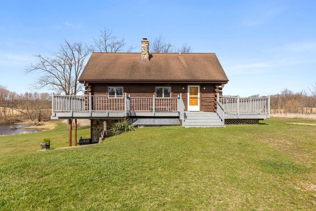 rear view of property with a yard, a deck, a chimney, and log siding
