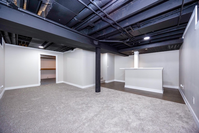 finished basement featuring bar, baseboards, and carpet floors