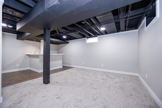 basement featuring carpet, baseboards, and bar area