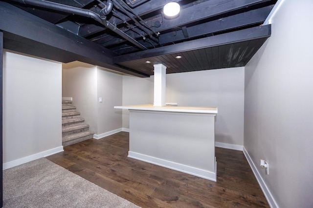 finished below grade area featuring stairway, baseboards, and dark wood-style floors