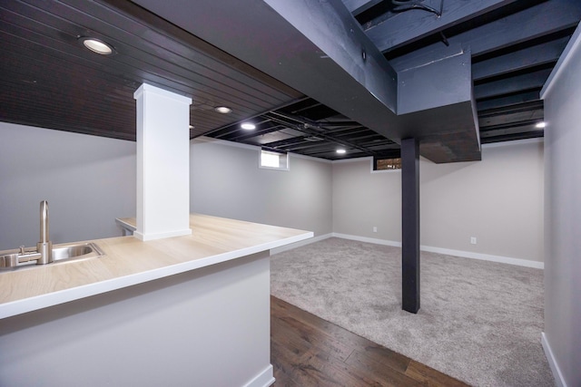 below grade area featuring a sink, dark wood-style flooring, baseboards, and dark carpet
