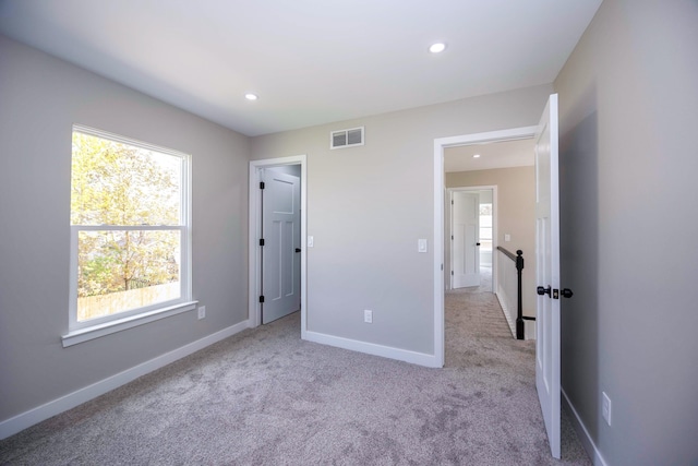 unfurnished bedroom featuring multiple windows, carpet flooring, and visible vents