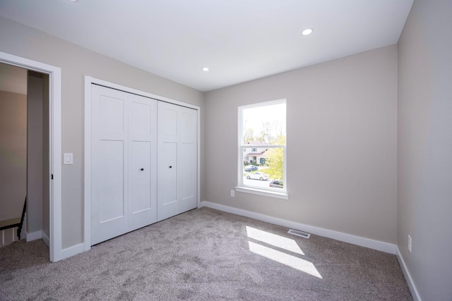 unfurnished bedroom featuring carpet flooring, a closet, visible vents, and baseboards