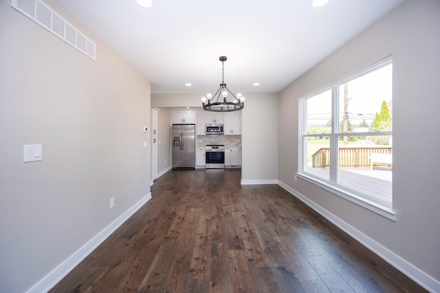 unfurnished dining area featuring a chandelier, baseboards, visible vents, and dark wood-type flooring