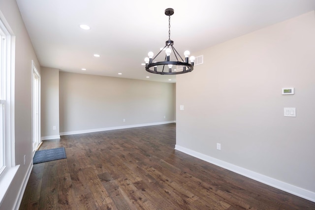 spare room featuring an inviting chandelier, dark wood-style flooring, and recessed lighting