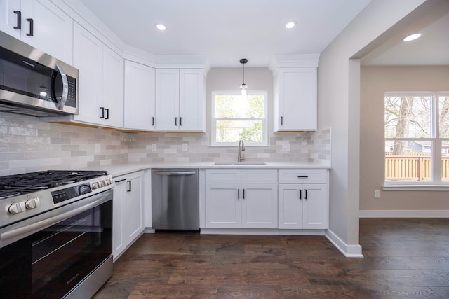 kitchen featuring stainless steel appliances, tasteful backsplash, a sink, light countertops, and white cabinets