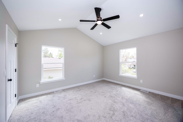 spare room with vaulted ceiling, visible vents, baseboards, and a ceiling fan