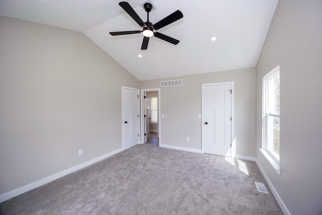 unfurnished bedroom with multiple windows, visible vents, carpet, and vaulted ceiling