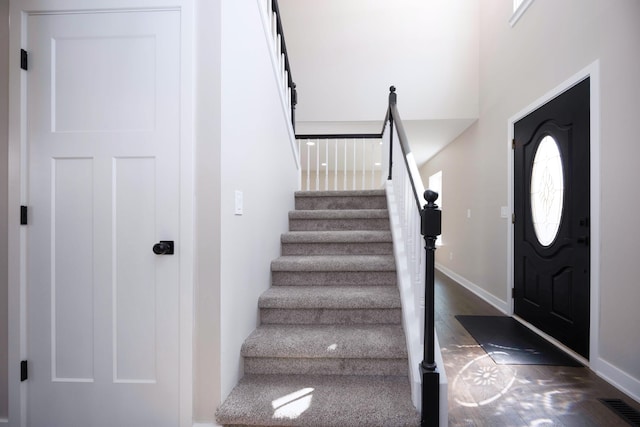foyer entrance with visible vents, dark wood-style flooring, baseboards, and stairs