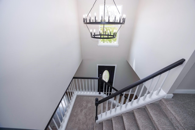 stairs featuring an inviting chandelier, baseboards, a towering ceiling, and carpet