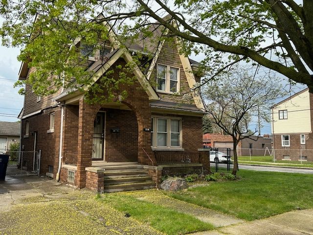 tudor house with brick siding, covered porch, and a gate