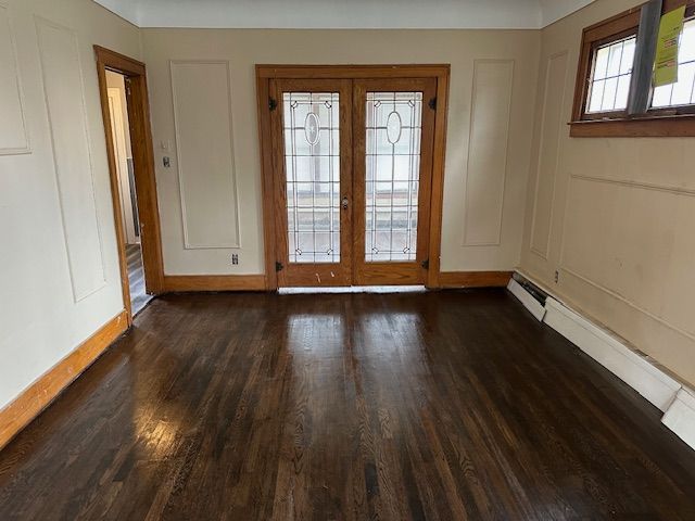 doorway with french doors, wood finished floors, baseboards, and baseboard heating