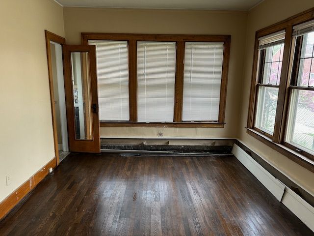 empty room with a baseboard radiator, baseboards, and wood finished floors