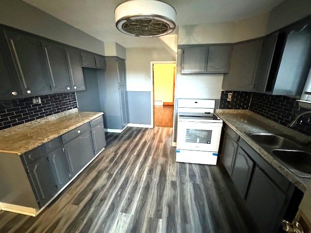 kitchen featuring white electric range, gray cabinetry, and tasteful backsplash