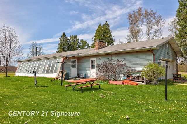 back of property with a chimney, a sunroom, and a lawn