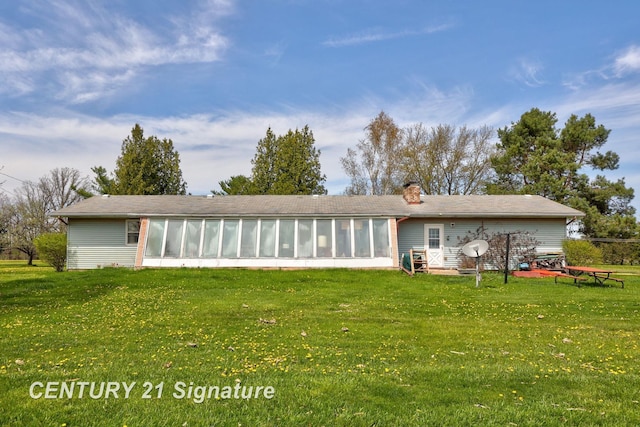 back of house with a sunroom, a chimney, and a lawn