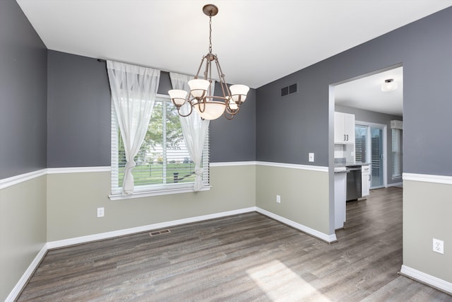 unfurnished dining area featuring a chandelier, wood finished floors, and baseboards