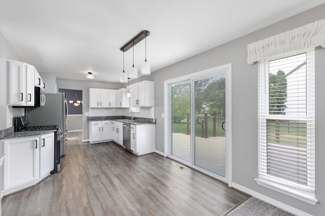 kitchen with appliances with stainless steel finishes, baseboards, dark wood-style floors, white cabinets, and a sink
