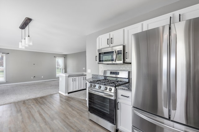 kitchen featuring stainless steel appliances, white cabinets, open floor plan, tasteful backsplash, and baseboards