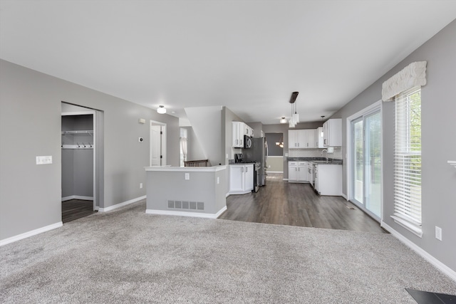 unfurnished living room with dark carpet, baseboards, and a sink
