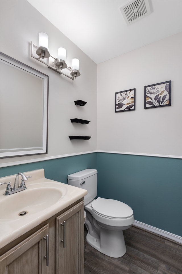 bathroom with wood finished floors, toilet, vanity, and baseboards