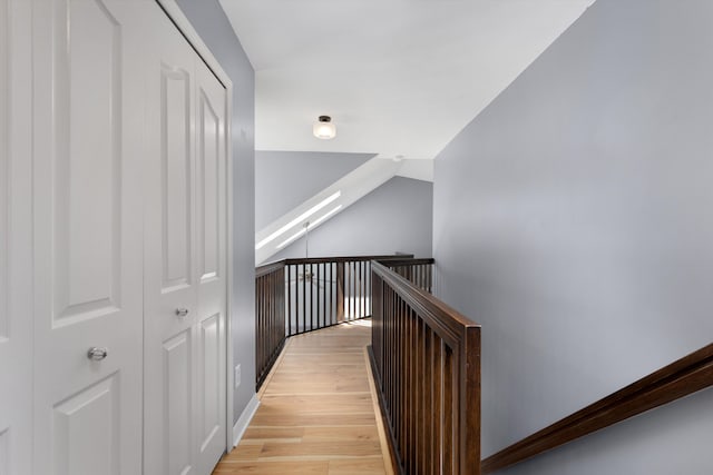hallway featuring an upstairs landing, light wood-type flooring, and baseboards