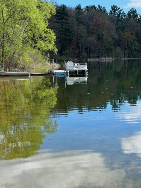 view of dock with a wooded view and a water view