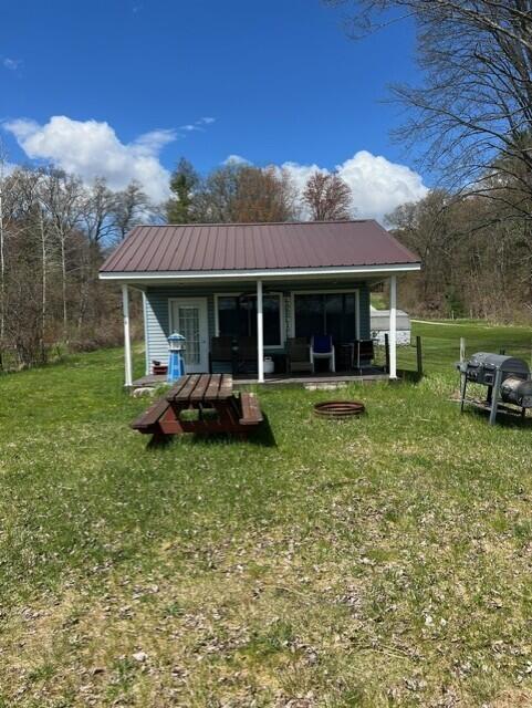 rear view of house featuring a yard, metal roof, and covered porch