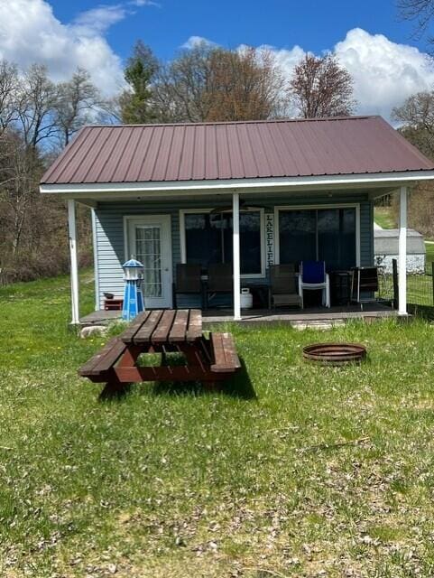 rear view of house featuring a porch, metal roof, and a lawn